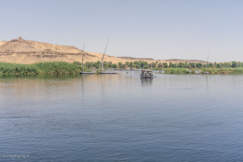 Panorama sul Nilo con barca, palme e dietro il deserto