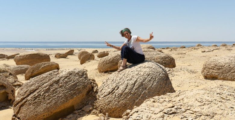 Martina seduta su una roccia nel deserto davanti al mare